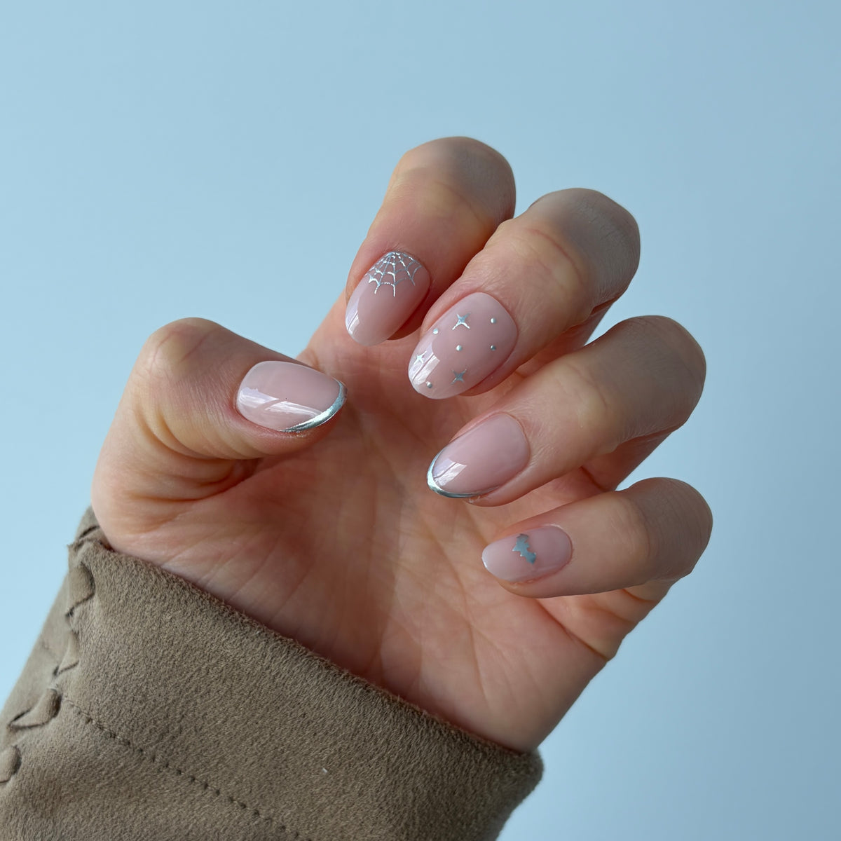 Salon quality reusable Candy Claws Press-On Nails in Nocturnal Short Oval Style. Light pink with 3d Silver Nail Art cobwebs, silver nail tip and stars.
