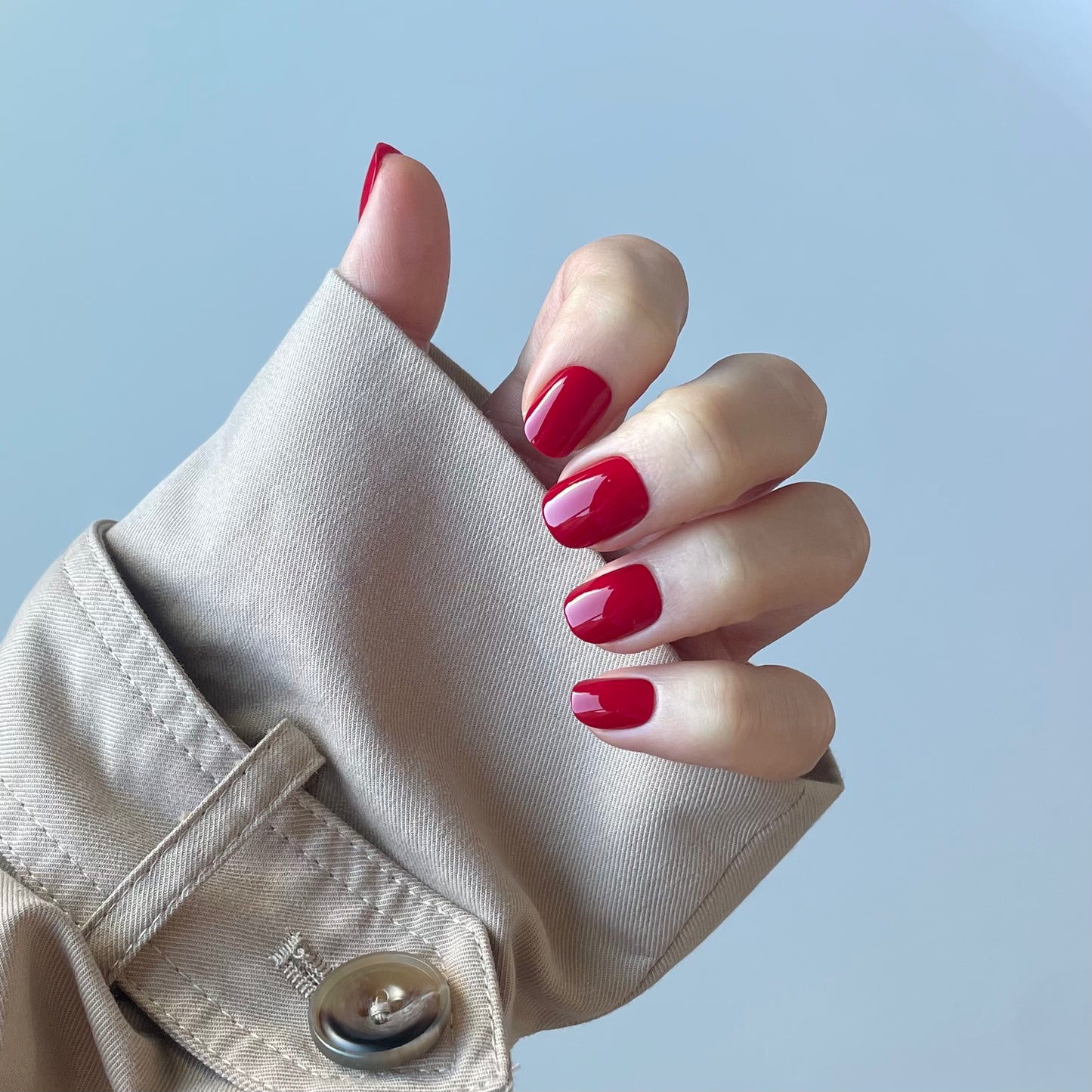 Womens hand with ruby red fake press-on nails also called false or acrylic nails