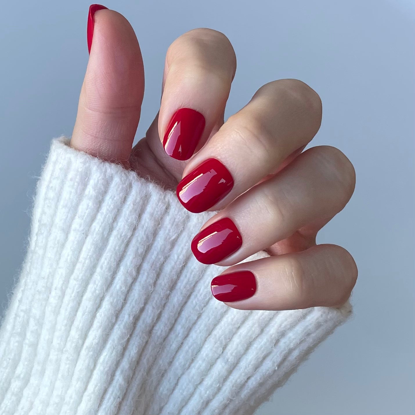 Womens hand with ruby red false press-on nails also called false or acrylic nails