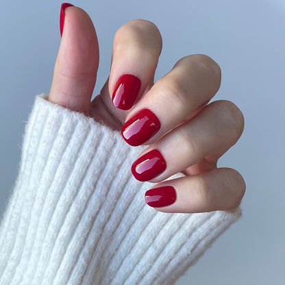 Womens hand with ruby red false press-on nails also called false or acrylic nails