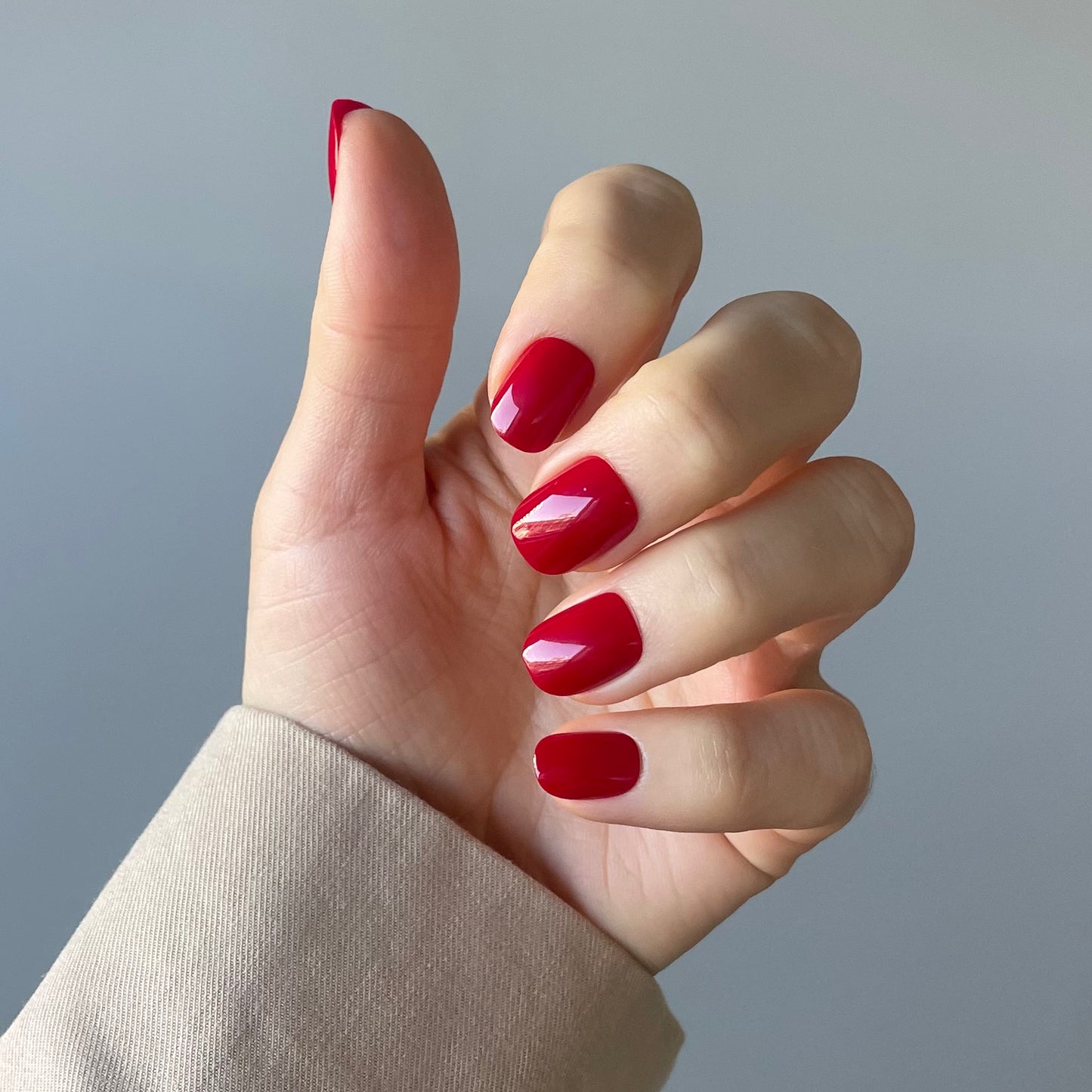 Womens hand with ruby red acrylic press-on nails also called false nails