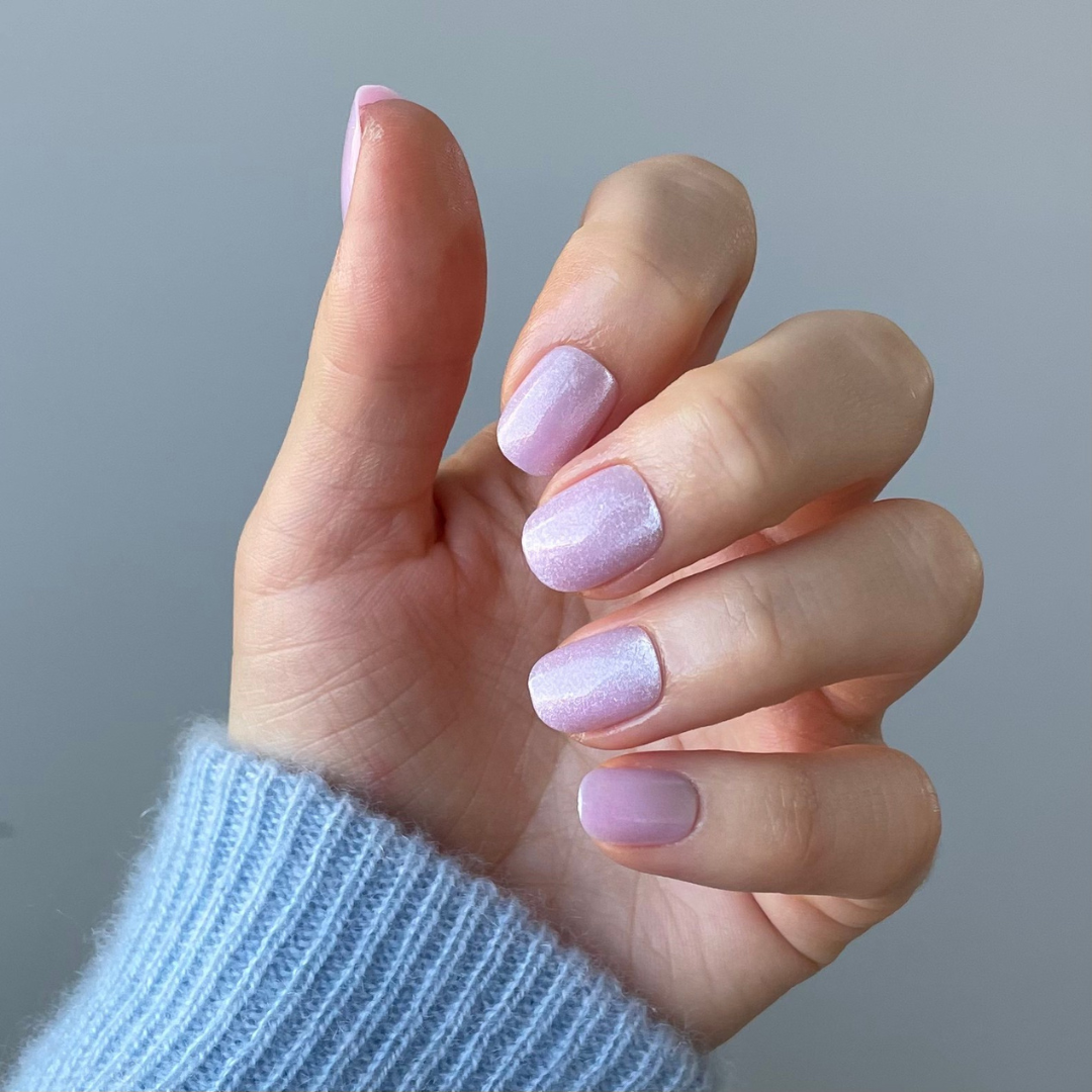 Hand with salon quality pink press-on cat-eye fake nails in the extra short style from Candy Claws. Removable and reusable.